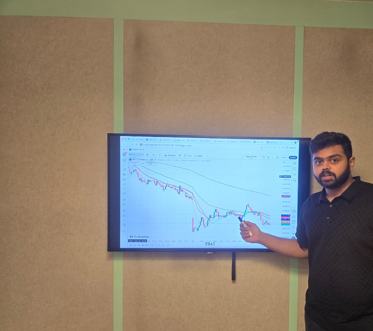 Mentor teaching chart analysis on a display during an in-person stock market class